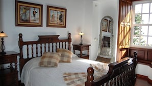 A bedroom with a wooden bed, two bedside tables with lamps, a mirror, and framed pictures on the wall. - Villa de Mazo, La Palma (Villa de Mazo)