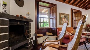 A cozy room with a fireplace, wooden chairs, a window, and a painting on the wall. - Villa de Mazo, La Palma (Villa de Mazo)
