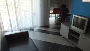 A living room with a sofa, a TV, and a dining table with chairs. - Apartment in Umag with Seaview, Balcony, Air condition, WIFI (235-1) (Umag)