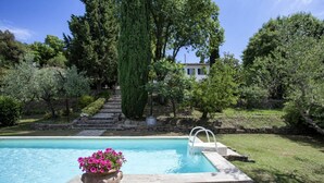 A swimming pool with a stone edge, a flower pot with pink flowers, and a stone staircase leading to a house. - House in Cortona with Pool, Wifi, A/C (Cortona)