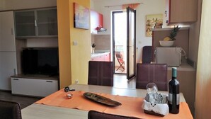 Un espace de vie compact comprenant un coin repas, une cuisine et donnant sur un patio extérieur.