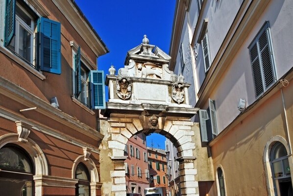 A narrow street with buildings on either side, featuring a prominent stone archway with decorative elements.