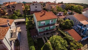 A residential area with houses, a paved courtyard, and a green building with a red roof.