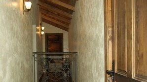 Una escalera de madera con barandilla de vidrio, que conduce a un cuarto con puerta de madera.