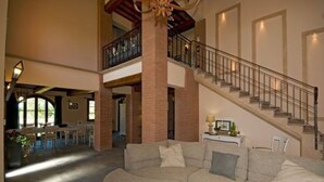 A spacious living area with a large sectional sofa, a staircase, and a dining area in the background. - Villa for 11 People in Tuscany with private pool (Peccioli)