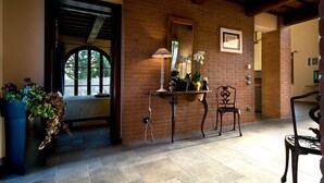 A room with a brick wall, a table with a lamp, a chair, and a potted plant. - Villa for 11 People in Tuscany with private pool (Peccioli)