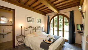 A bedroom with a bed, a bedside table, a mirror, and a window with curtains. - Villa for 11 People in Tuscany with private pool (Peccioli)