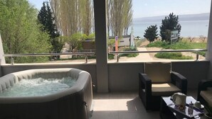 Ein Whirlpool auf einem Balkon mit Blick auf ein Gewässer und Bäume.