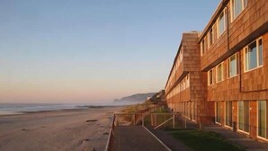 Un edificio frente a la playa con un camino largo y recto que conduce a la orilla.