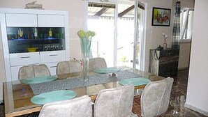 A dining area with a glass table, six chairs, and a white cabinet with glass doors.