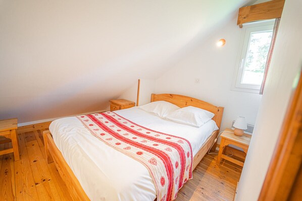 A single-bed room with a wooden headboard, a bedside table, and a nightstand.