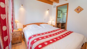 A bedroom with a wooden bed, two bedside lamps, a mirror, and a red curtain with heart patterns.