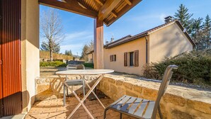 Eine Terrasse im Freien mit Tisch und Stühlen, einer Steinmauer und einem Gebäude im Hintergrund.
