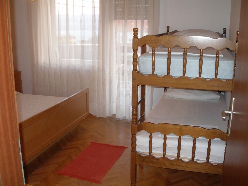 A bunk bed with a wooden headboard and a red rug on a wooden floor.