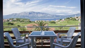 A balcony with two white plastic chairs and a small table, overlooking a scenic view of mountains and a body of water. - Apartment in Lumbarda with Seaview, Balcony, Air condition, WIFI (4432-1) (Lumbarda)