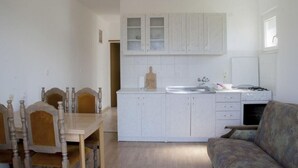 A compact kitchen with white cabinets, a dining table with chairs, and a sofa. - Apartment in Lumbarda with Seaview, Balcony, Air condition, WIFI (4432-1) (Lumbarda)
