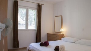 A bedroom with a bed, a bedside table with a lamp, a mirror, and a window with curtains. - Apartment in Lumbarda with Seaview, Balcony, Air condition, WIFI (4432-1) (Lumbarda)