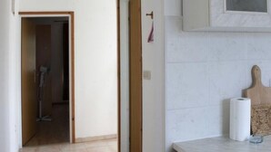 A hallway with a door leading to a room, a ceiling light, and a kitchen area with a countertop and cabinets. - Apartment in Lumbarda with Seaview, Balcony, Air condition, WIFI (4432-1) (Lumbarda)