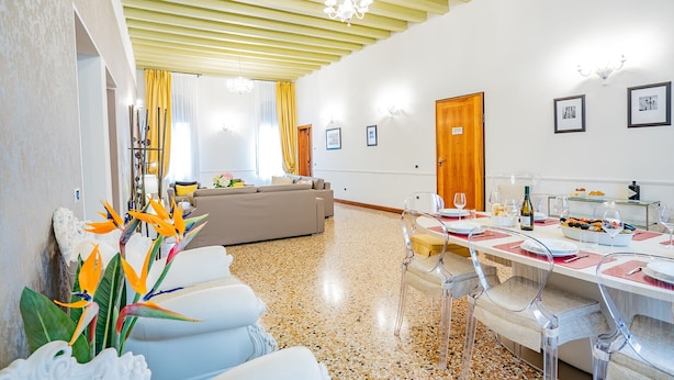 A dining area with a table set for a meal, a sofa, and a chandelier. - Ca' Del Monastero 4 Collection (Venezia)