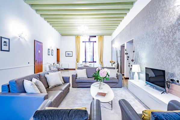 A modern living room with a sofa, armchairs, a coffee table, and a TV.