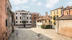 A historic square with cobblestone pavement, traditional buildings, and a fountain. - Ca' Del Monastero 4 Collection (Venezia)