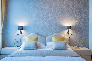 A neatly made bed with two pillows, a bedside table with a lamp, and a wall with a textured pattern. - Ca' Del Monastero 4 Collection (Venezia)