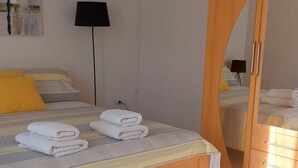 Un lit bien fait, avec des serviettes, une lampe de chevet et un grand miroir.