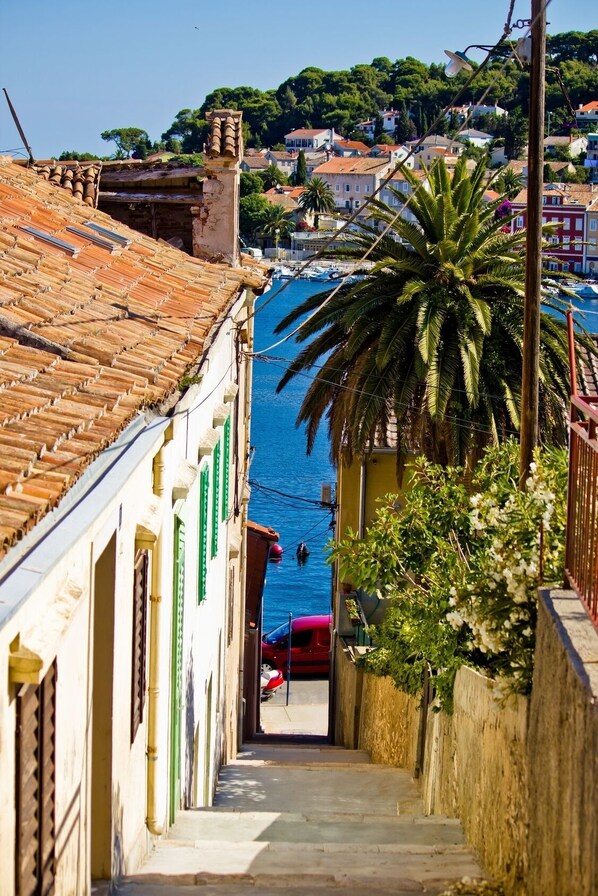A narrow alleyway leading to a waterfront with buildings on either side.
