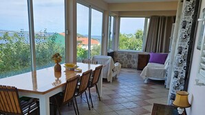 Amplia sala de estar con mesa y sillas de comedor, un sofá y vistas al exterior.