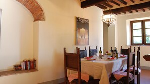 Ein Essbereich mit einer Ziegelbogenarchitektur, einer Kristallleuchter und einem für ein Essen gedeckten Tisch.