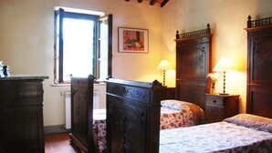 Ein Schlafzimmer mit zwei Betten, Holzmöbeln, einem Fenster und einem Bild an der Wand.