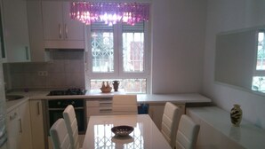 A modern kitchen with white cabinets, a dining table, and a window with decorative curtains. - Apartment in Zagreb with Balcony, WIFI, Washing machine (4292-1) (Zagreb)