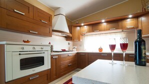 A modern kitchen with wooden cabinets, a white stove, and a large island with two wine glasses.