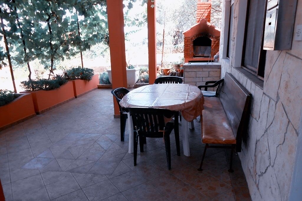 A patio with a round table and chairs, a bench, and a brick oven.