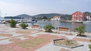 A waterfront promenade with benches and potted plants, a marina with boats, and buildings in the background. - Apartment in Poljana with Seaview, Terrace, Air condition, WIFI (4232-1) (Poljana)