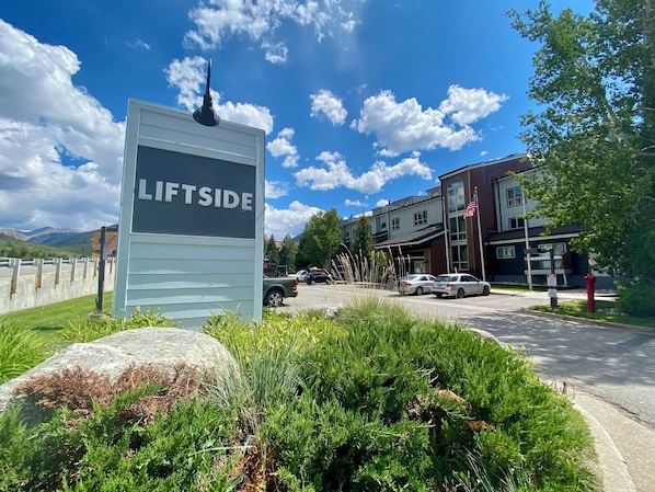 A sign with 'LIFTSIDE' written on it, a parking area with cars, and a building with a flag.