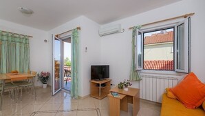 A living room with a sofa, a TV, a dining table with chairs, and a sliding glass door leading to an outdoor area. - Apartment in Bol with Balcony, Air condition, WIFI, Dishwasher (5217-7) (Bol)