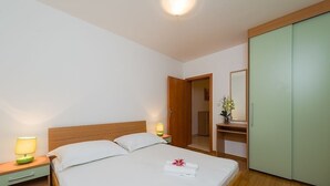 A hotel room with a single bed, bedside tables with lamps, a wardrobe, and a mirror. - Apartment in Bol with Balcony, Air condition, WIFI, Dishwasher (5217-7) (Bol)
