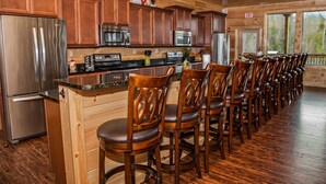 Eine Küche mit Holzausbau, Edelstahlgeräten und einer langen Bar mit Holzhockern.