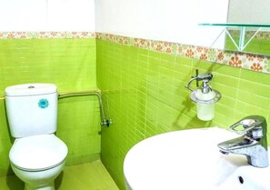 A bathroom with a toilet, a sink, and a glass shelf.