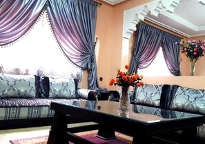 A living room with a sofa, a coffee table, and a vase with flowers.