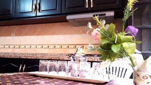 A kitchen with dark cabinets, a tiled backsplash, and a table with a patterned tablecloth. - Level of villa in Marrakech 3557 (Marrakech)