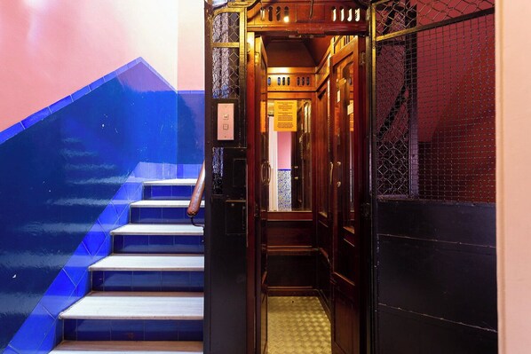 A staircase with a handrail, a wooden door with a sign, and a patterned floor.