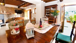 Un espacio de sala acogedor con chimenea de piedra, muebles de madera y una mesa de comedor preparada para una comida.