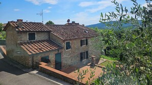 Un edificio de piedra con techo de tejas, una chimenea y una pequeña ventana con contraventanas.