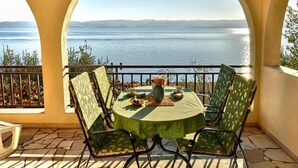 Een ronde tafel met stoelen op een balkon met uitzicht op een waterlichaam.