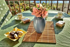 A table set with a vase of flowers, two cups, and a plate of pastries. - Apartment in Pisak with Seaview, Terrace, Air condition, WIFI (77-2) (Pisak)