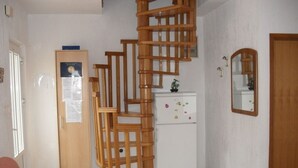 A room with a wooden staircase, a white refrigerator, a wooden cabinet, and a mirror on the wall. - Apartment in Lopar with Balcony, Air condition, WIFI (87-3) (Lopar)