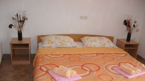 A neatly made bed with a patterned bedspread, two pillows, and two side tables with vases of dried flowers. - Apartment in Lopar with Balcony, Air condition, WIFI (87-3) (Lopar)