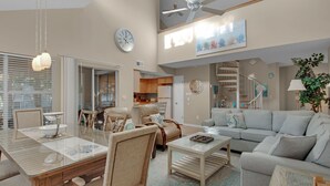 Un salón espacioso con comedor, una escalera y una cocina al fondo.